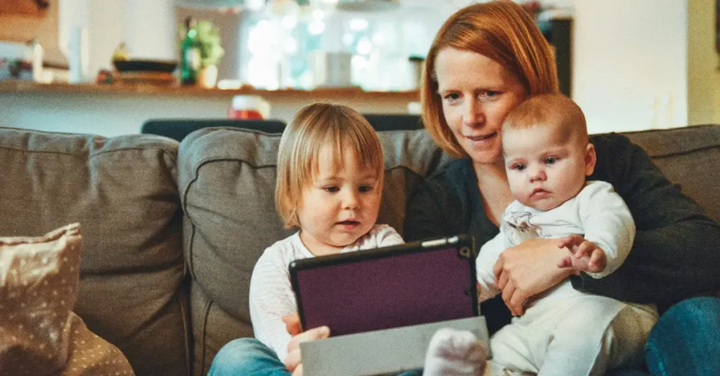 A mother and two children sitting on the sofa watching iPad