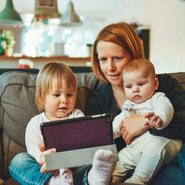 A mother and two children sitting on the sofa watching iPad