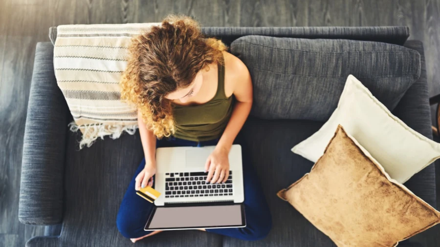 high angle shot of a young woman using a laptop and credit card on the sofa at home